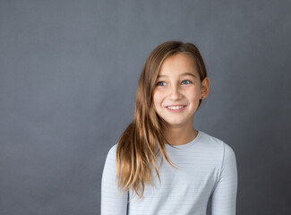 Portrait of a young happy girl on grey background with space for text - 463842793