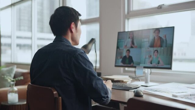 Back rear view smart millennial asian male employee using computer monitor, intent online video call brainstorms meeting with diverse colleagues and male executive manager, working from home concept