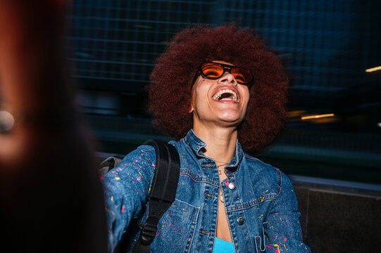 Happy woman laughing while taking selfie on dark street