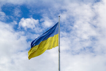 Ukrainian flag on a background of blue sky and white clouds