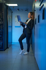 Technician using laptop in server room of data center