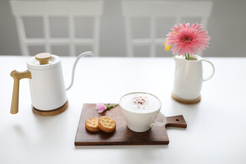 cappuccino coffee and sandwich cookie on white wooden table