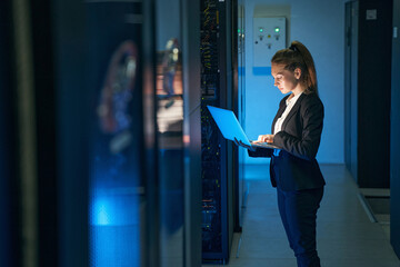 Female engineer working in server room at modern data center - obrazy, fototapety, plakaty