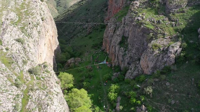  Aerial footage highline in the mountains.  Female slackliner in  rocky mountains at countryside. Rock climbing. Rope jump. 