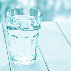 A glass with pure clear melt water stands on a white table