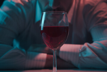 Glass of wine close up. Man leaning over a glass of alcohol.