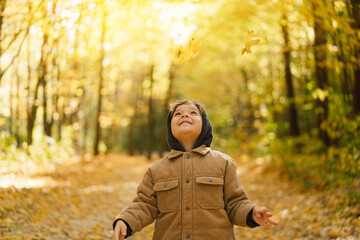 Happy little child baby boy laughing and playing in the autumn day. Child play with leaves. Autumn outdoor activity for family with kids.