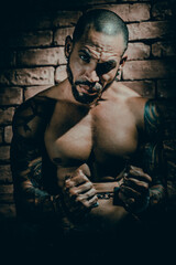 A bandit or rapist in tattoos is imprisoned in solitary confinement. Hands in handcuffs. A...