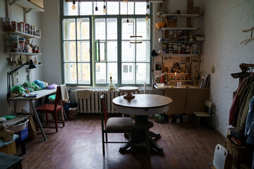 Pottery craftsman workplace: creative art studio interior with table, professional equipment tools and space for working with clay, potter and ceramics. Craftsmanship and artistic workshop indoors