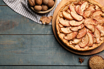 Delicious apple pie, sugar and walnuts on light blue wooden table, flat lay. Space for text