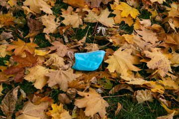  A disposable used blue medical mask is thrown to the ground  during the COVID19 coronavirus pandemic. Concept of modern version of environmental pollution by medical masks.