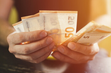 business man counting money. rich male hands holds and count cash banknotes of 50 euros bills or notes currency. flare