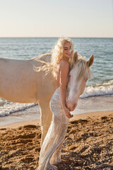 beautiful girl with white hair like an angel stands on the beach with a white horse