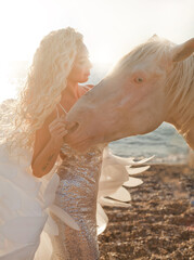 beautiful girl with white hair like an angel stands on the beach with a white horse