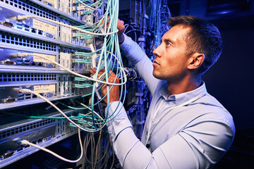 Skilled focused system administrator inspecting fiberl cabling