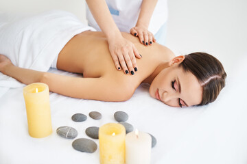 Young woman enjoying relaxing back massage at spa salon