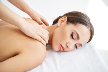 Close up portrait of young woman enjoying relaxing back massage at spa salon.