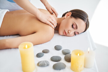 Fototapeta na wymiar Young woman enjoying relaxing back massage at spa salon