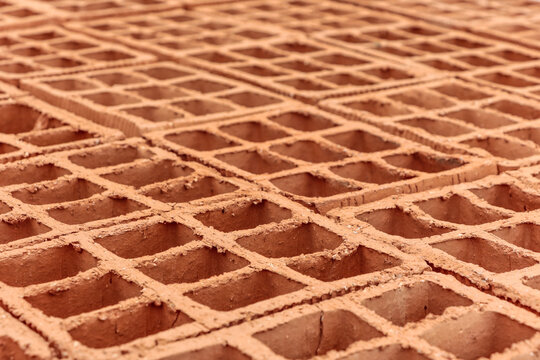 Pile of clay bricks used for building masonry house. The image the bricks are laid out, focusing on their holes.
