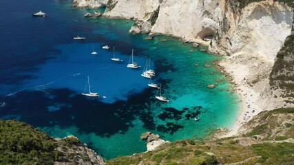 Aerial drone video of tropical white rocky bay of Erimitis with turquoise clear waters and anchored luxury sail boats, island of Paxos, Ionian, Greece