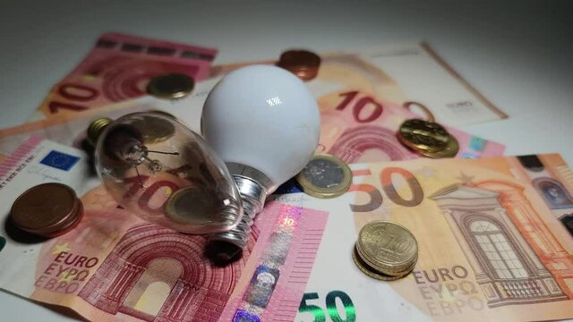 Luz variable sobre dinero y bombillas queriendo mostrar el precio de la electricidad