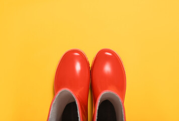 Red rubber boots on orange background, top view