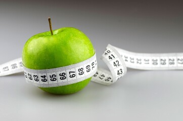 Apple and Tape Measure on Grey Background