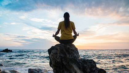 Yoga woman in Lotus position practicing yoga and meditation. outdoors on the evening ocean