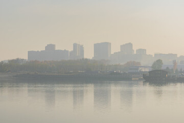 Fototapeta na wymiar View of the city from the river. Smog air pollution 