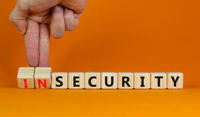Security or insecurity symbol. Businessman turns wooden cubes, changes words insecurity to...