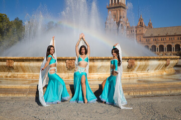 three beautiful belly dancers dressed in light blue dancing in a city square. Belly dancing and belly dancing concept, folklore from Africa.