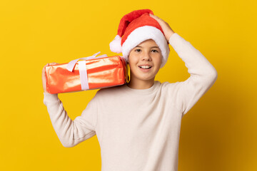 portrait of a happy little boy holding a gift box isolated over yellow background.