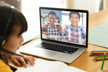Fototapeta na wymiar Asian girl using laptop for video call, with smiling high elementary school pupils on screen