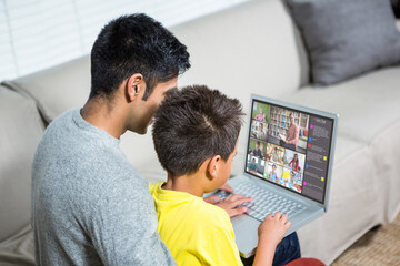 Biracial boy with father using laptop for video call, with elementary school pupils on screen - Powered by Adobe