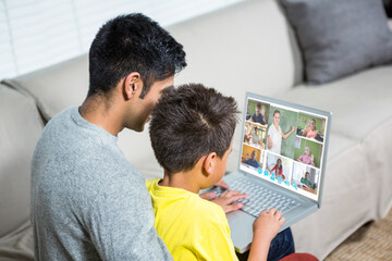 Biracial boy with father using laptop for video call, with elementary school pupils on screen