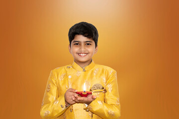Indian Smart boy portrait in kurta holding diwali diya on dark background