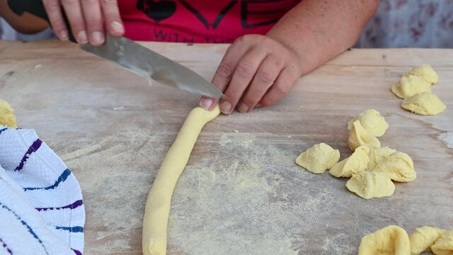 Bari, Puglia, Italy. August 2021. Close-up footage of a senior lady's skilled hands as she prepares orecchiette: local pasta specialties. With quick gestures the raw pasta becomes orecchietta.