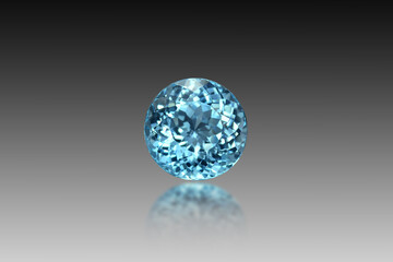 Natural Swiss blue topaz gemstone loose faceted setting for making jewelry. Round shape. Front view. Gray gradient background, blury half reflection effect. Isolated. Gemology theme. Irradiated stone.