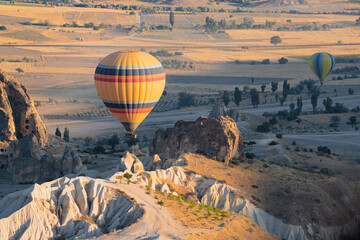 hot air balloon with rainbow colors pattern rising over the Cappadocian valley