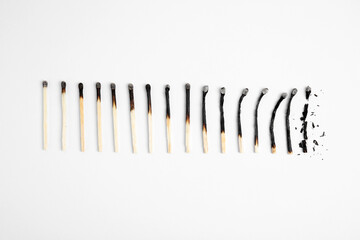 Different stages of burnt matches on white background, flat lay