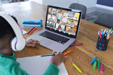 Fototapeta na wymiar African american boy using laptop for video call, with diverse elementary school pupils on screen