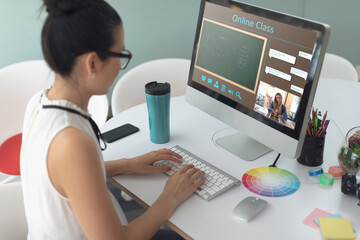 Asian woman using computer for video call, with class on screen