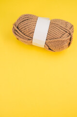 Vertical shot of isolated soft beige yarn ball on an yellow background