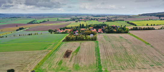 Aerial view of a small village at the edge of the Elm in Lower Saxony, Germany, with agricultural land in front of it