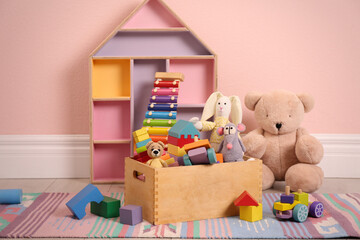 Set of different cute toys on floor near pink wall