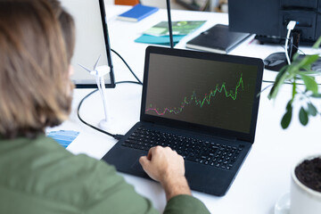 Caucasian businesswoman sitting at desk using laptop with graph and statistical data on screen