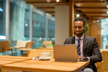 Fototapeta na wymiar Young African businessman in coffee shop using laptop computer