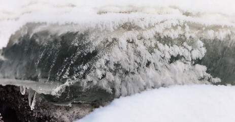 Icicles and frost on a snow-covered frozen river