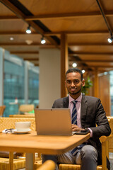 Young African businessman in coffee shop using laptop computer