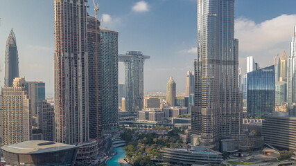 Fototapeta premium Skyscrapers rising above Dubai downtown timelapse, mall and fountain surrounded by modern buildings aerial top view